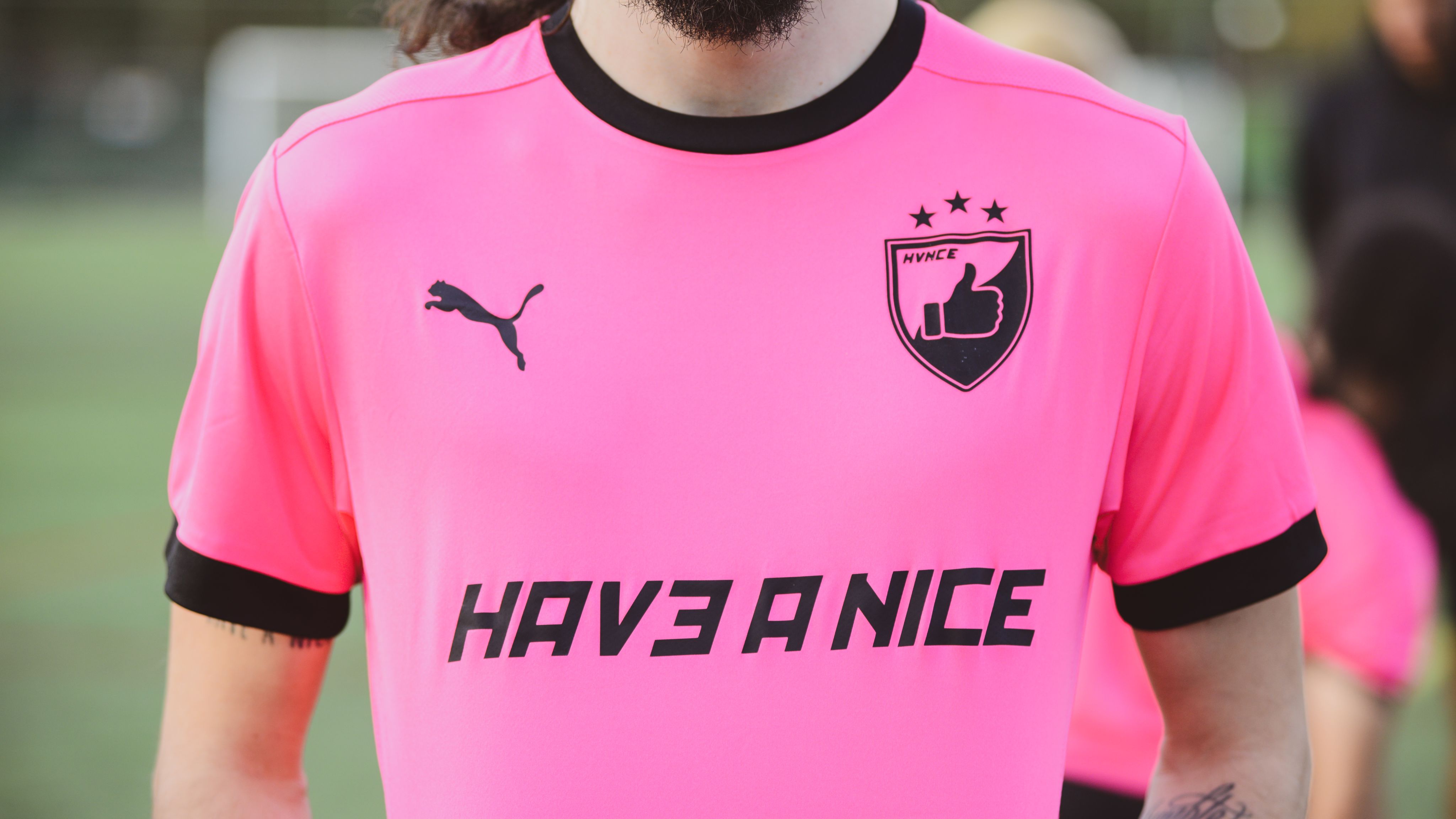 Up close of man wearing a bright pink shirt that reads Have a Nice on the front