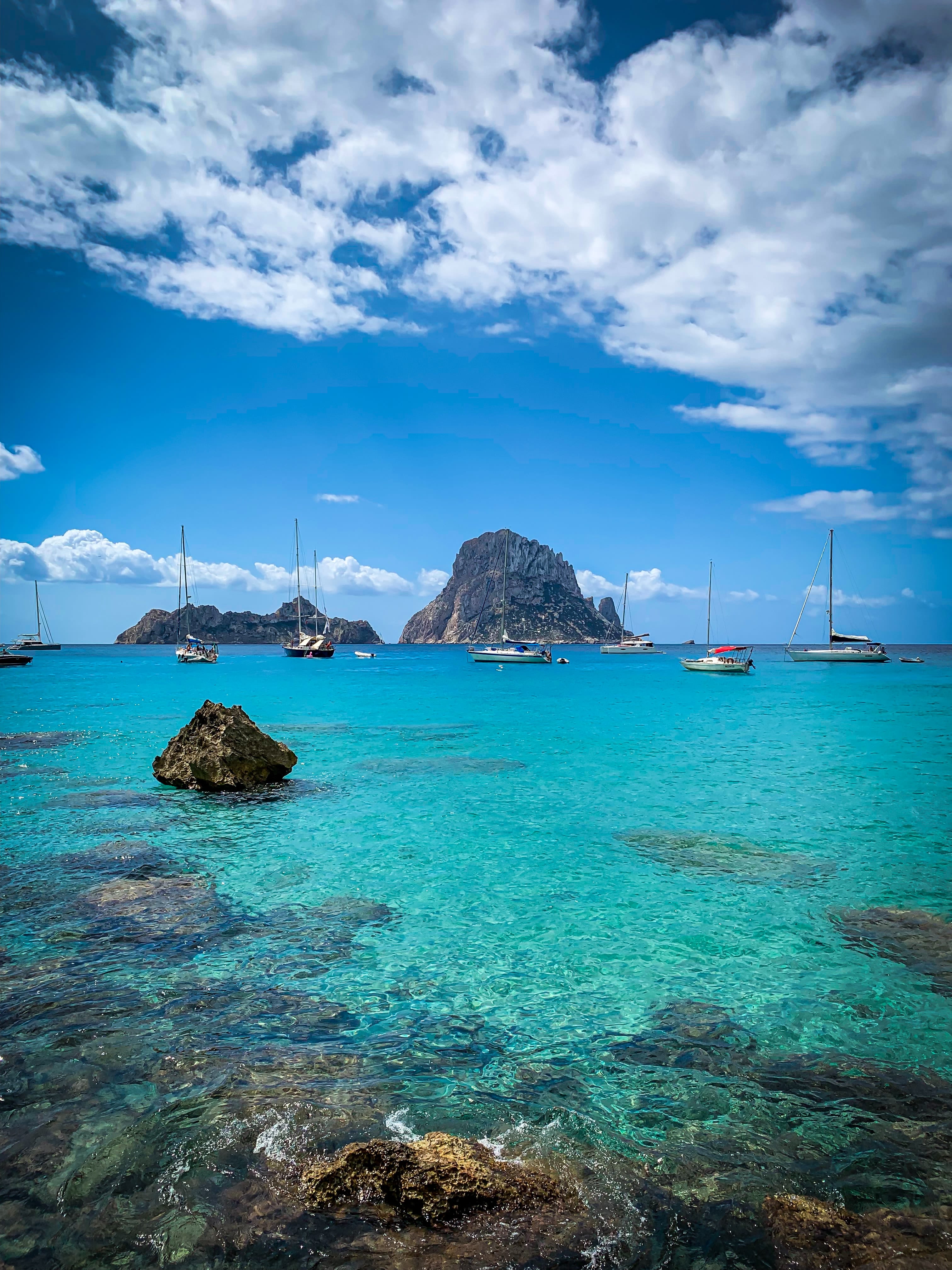 different yachts on blue sea viewing mountain under white and blue sky during daytime