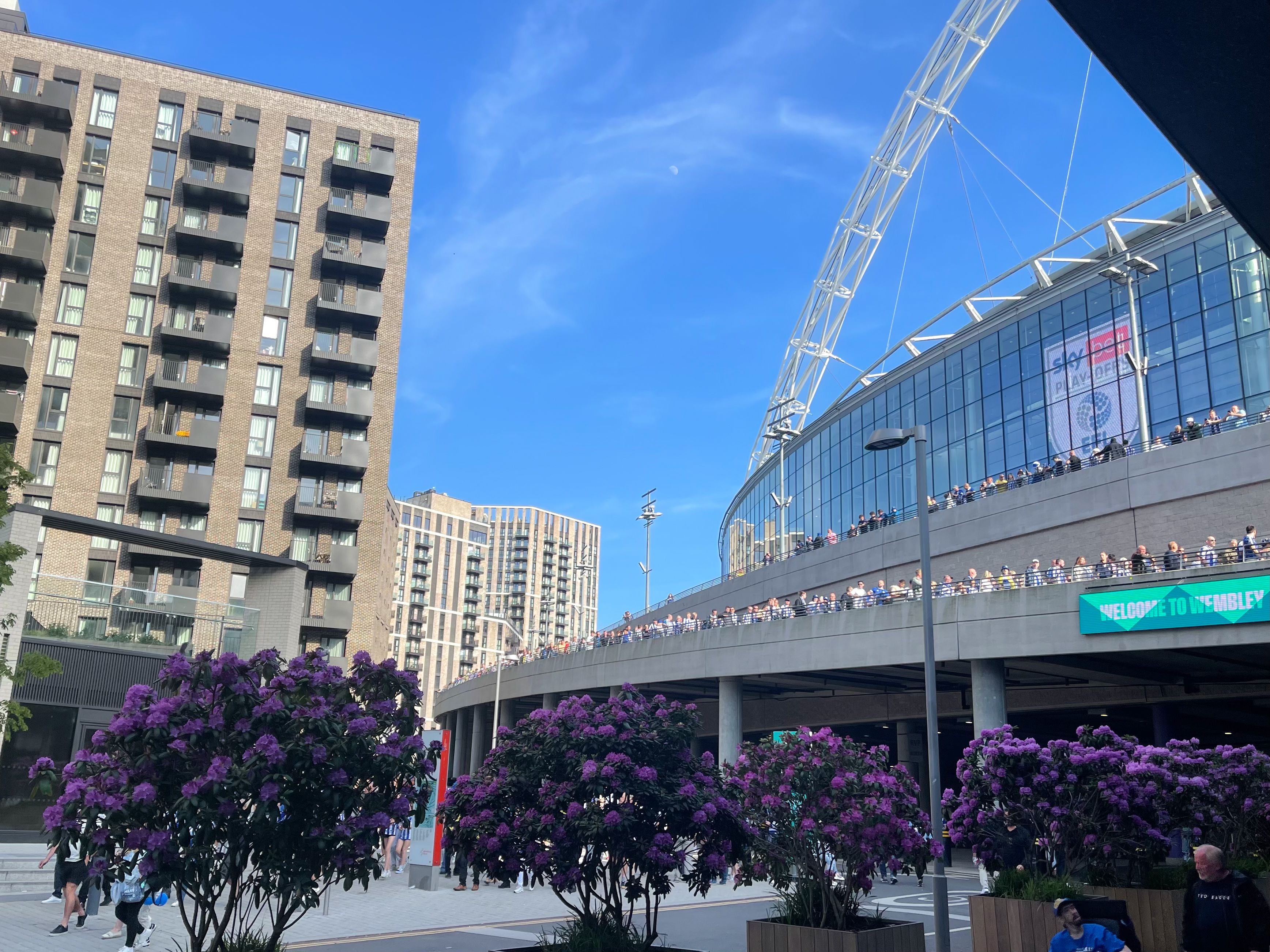 Wembley Stadium with part of the arch seen overhead and an apartment building to the left.